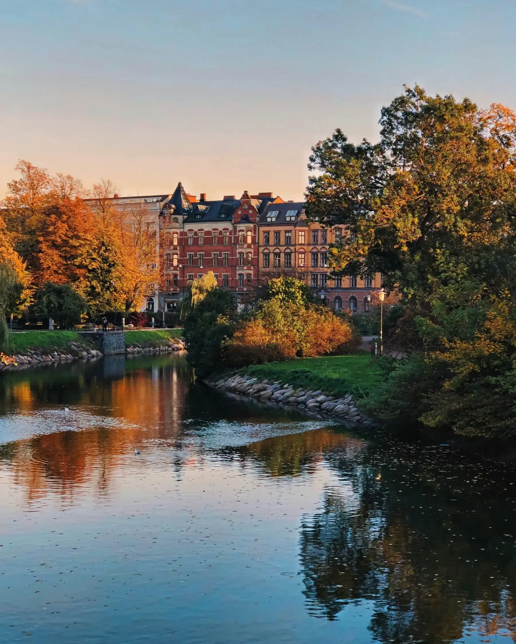 Kanal i Malmö i höstljus, med gamla stenhus och träd i orange färger som speglas i vattnet.